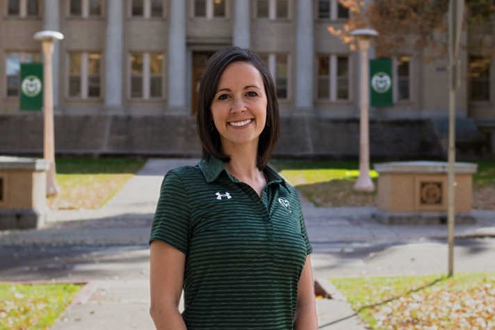 photo Jenna Waldvogel in green polo shirt in front of Admin building.
